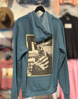 Blue hoodie with graphic design on a hanger against a clothing store background
