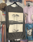 Gray sweatshirt with B&W photo of trees and a lake. Hanging against blurred background of store.