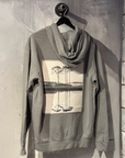 Gray hoodie with a nature-themed graphic on a hanger against a textured wall.