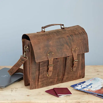 Brown leather satchel on a wooden surface with a light blue background