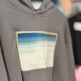 Gray hoodie with a colorful patch on a hanger
