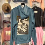 Blue hoodie with graphic design on a hanger against a clothing store background
