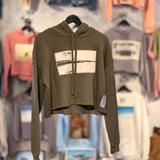 Cropped hoodie with a western lake design on a blurry store background 