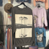 Gray sweatshirt with B&W photo of trees and a lake.  Hanging against blurred background of store.