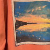 Orange sweatshirt with a photo of a sunset over a lake.