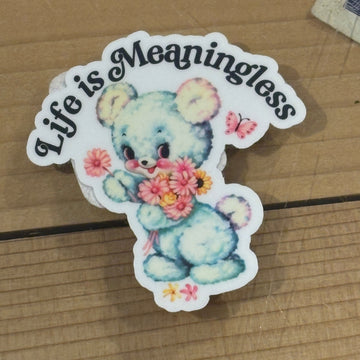Sticker with a bear design and text 'Life is Meaningless' on a cardboard background