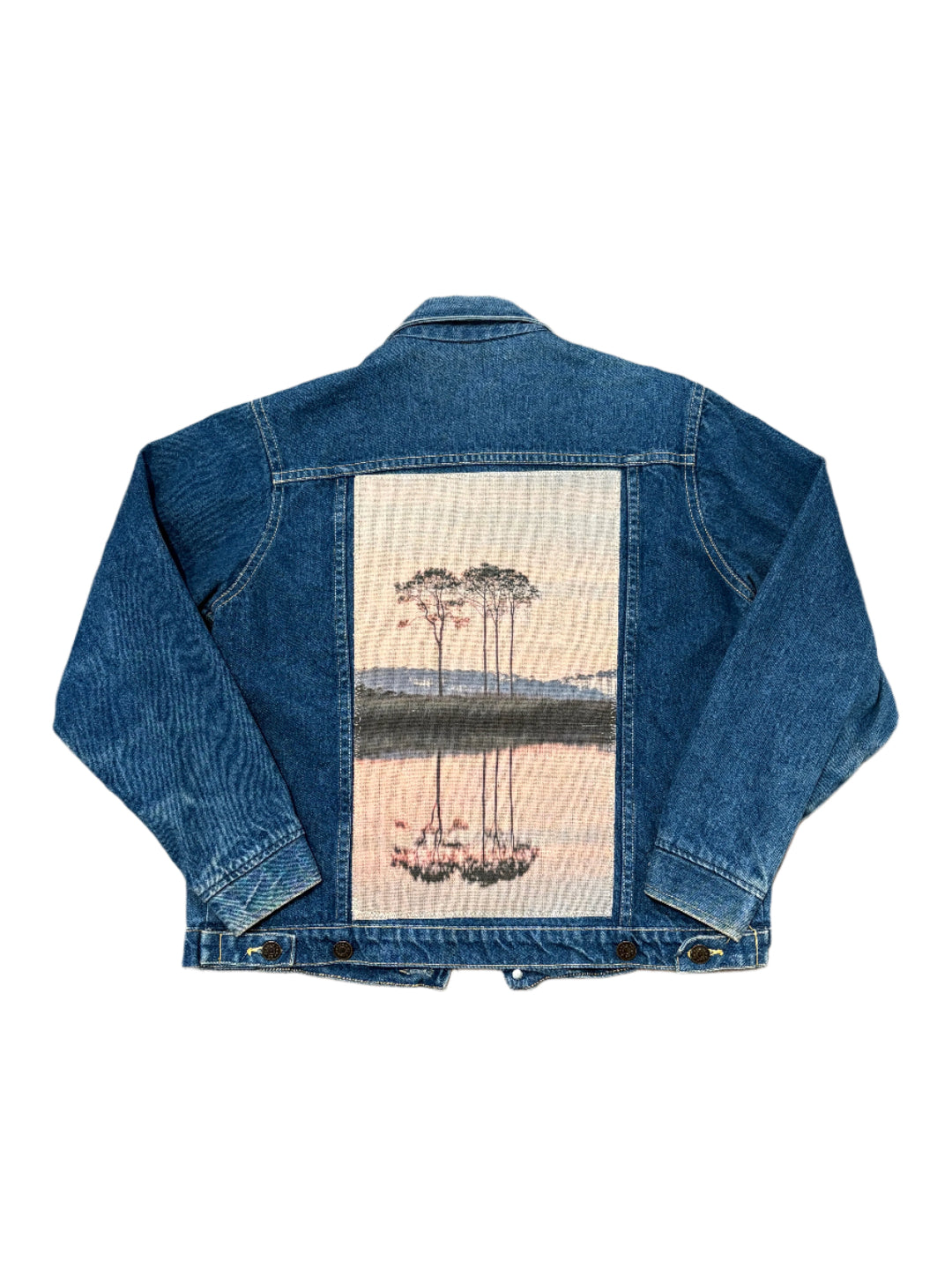 Blue denim jacket with a western lake sunset on the back against a white background