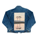 Blue denim jacket with a western lake sunset on the back against a white background