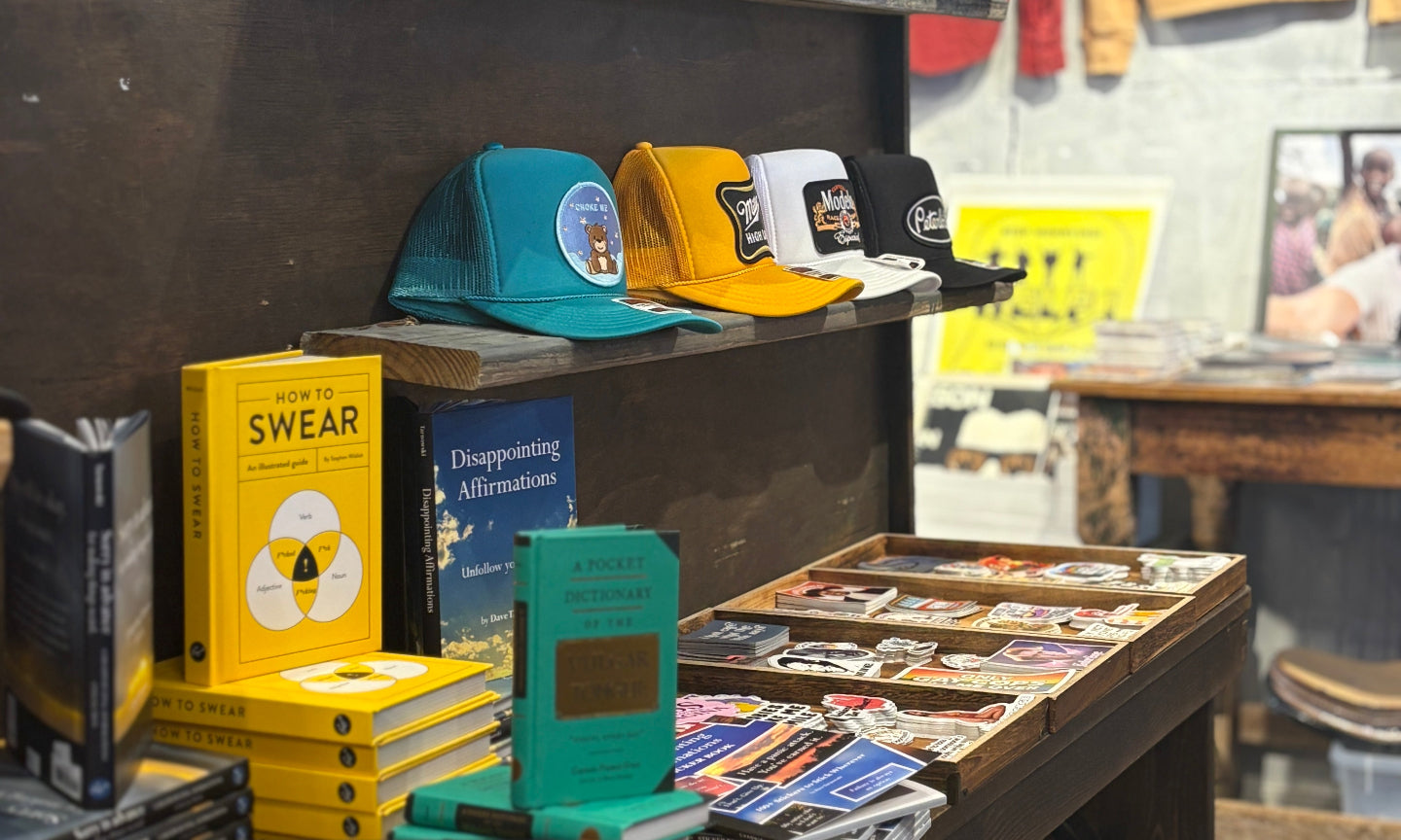 Display of merchandise including hats, books, and stickers in a store setting.