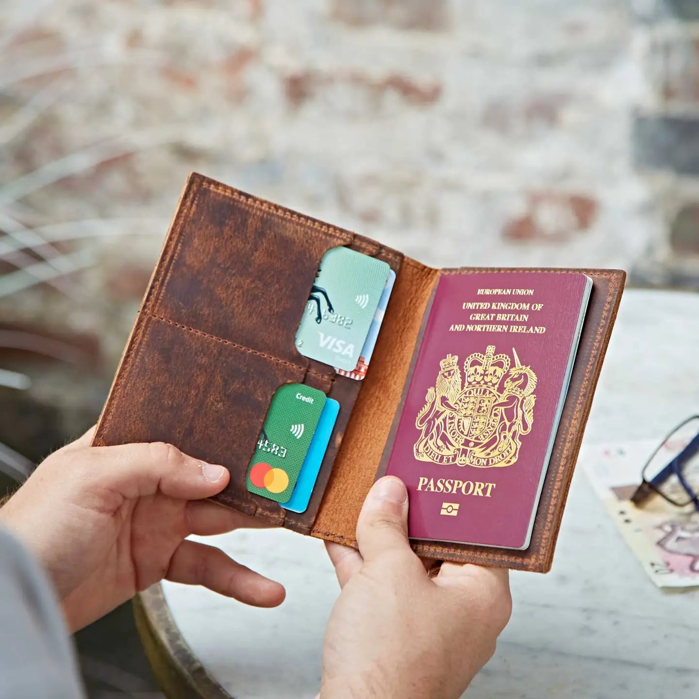 Brown leather wallet with cards and a passport held by a person against a blurred background