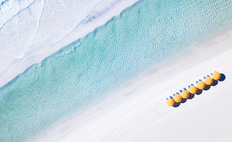 Aerial view of yellow beach umbrellas along turquoise Gulf water and white sand on Florida’s 30A coast.