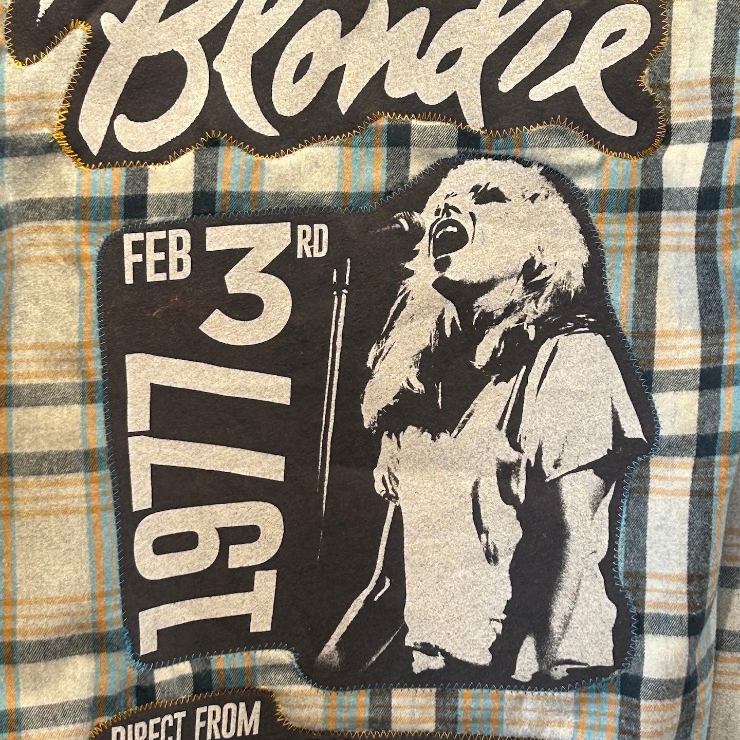 Plaid fabric with 'Blondie' design featuring a person and text on a plaid background