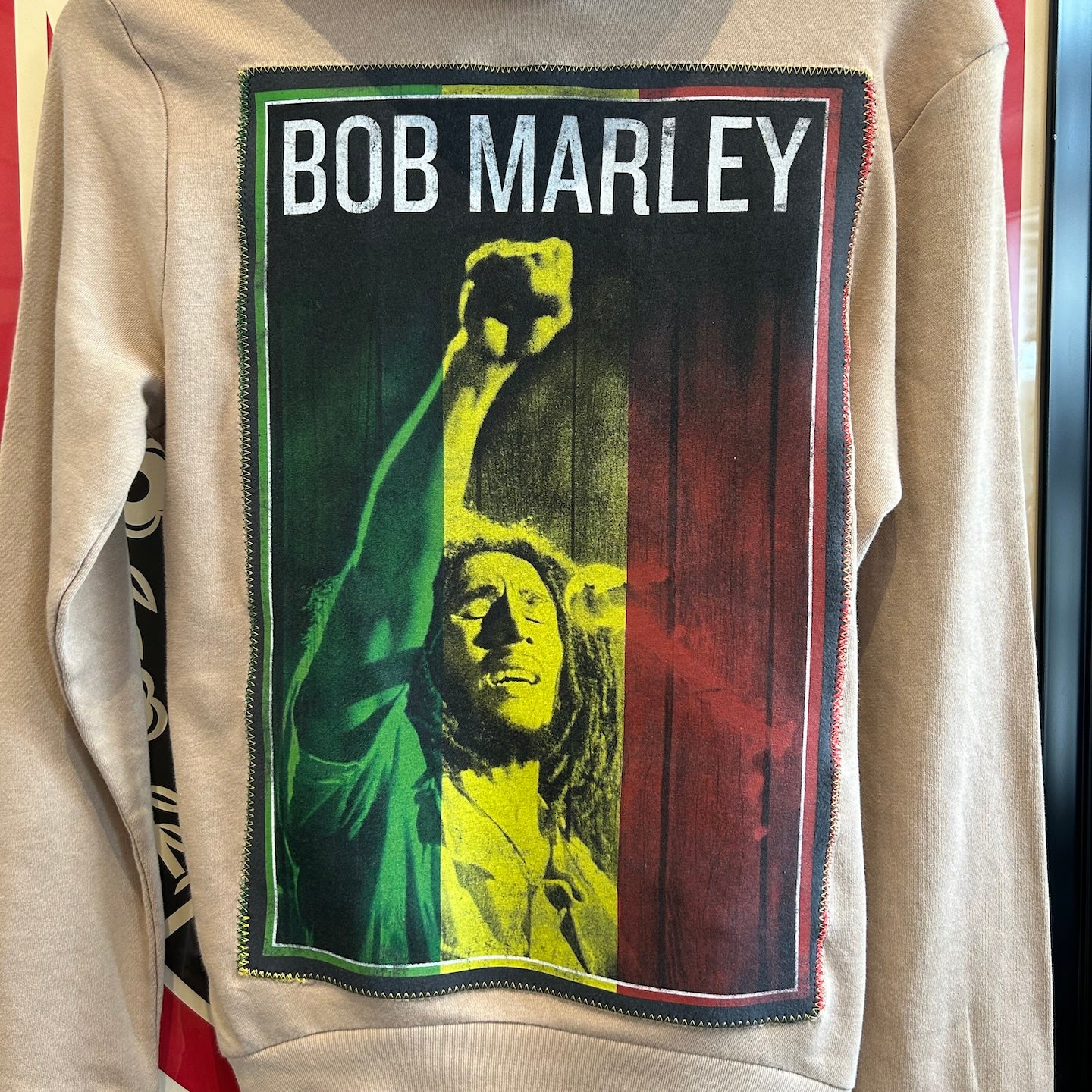 Beige hoodie with Bob Marley graphic on a red and white background