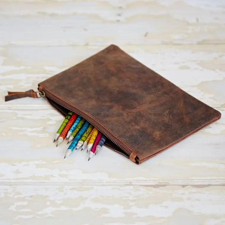Brown leather pencil case with colorful pencils on a light wooden surface