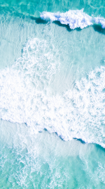 Aerial photo of turquoise waves breaking over white sand at Grayton Beach, Florida.