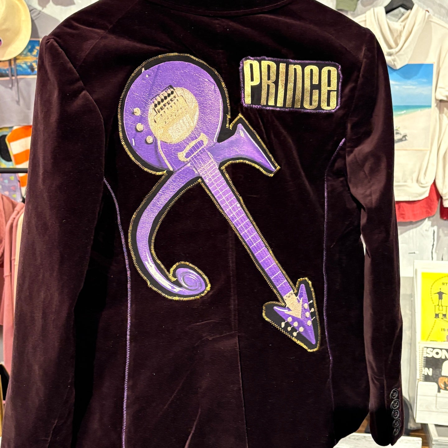 Black jacket with Prince logo on a hanger in a store setting