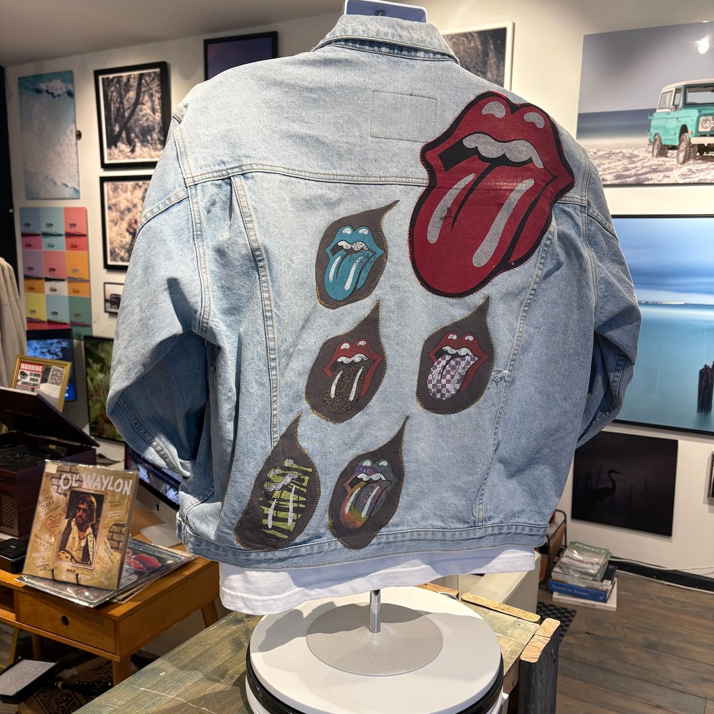 Denim jacket with Rolling Stones patches on a mannequin in a store setting.