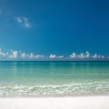 Turquoise Gulf water and white sand under a clear blue sky on Florida’s Emerald Coast.