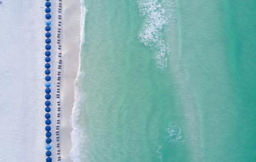 Aerial photo of blue beach umbrellas along turquoise Gulf water and white sand at WaterColor Beach, 30A.