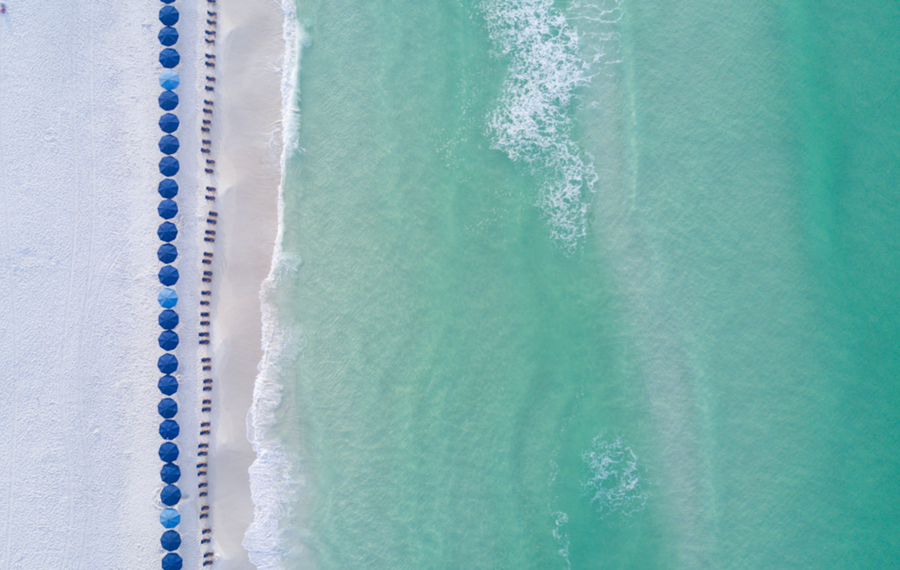Aerial photo of blue beach umbrellas along turquoise Gulf water and white sand at WaterColor Beach, 30A.