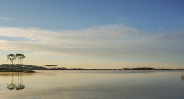 Sunrise photograph of Western Lake with calm water reflecting blue sky and longleaf pines, Grayton Beach Florida.