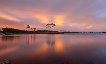 Sunset photograph of Western Lake with longleaf pine reflections and orange-pink sky, Grayton Beach Florida.