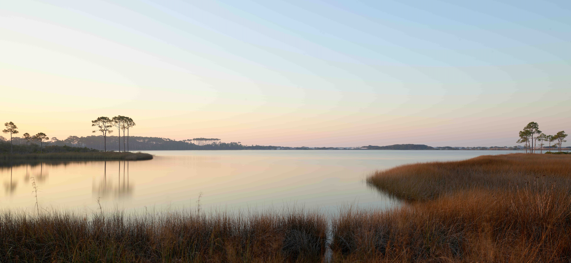 Western Lake sunset photograph showing warm sawgrass and pine tree reflections on calm water, Grayton Beach Florida.